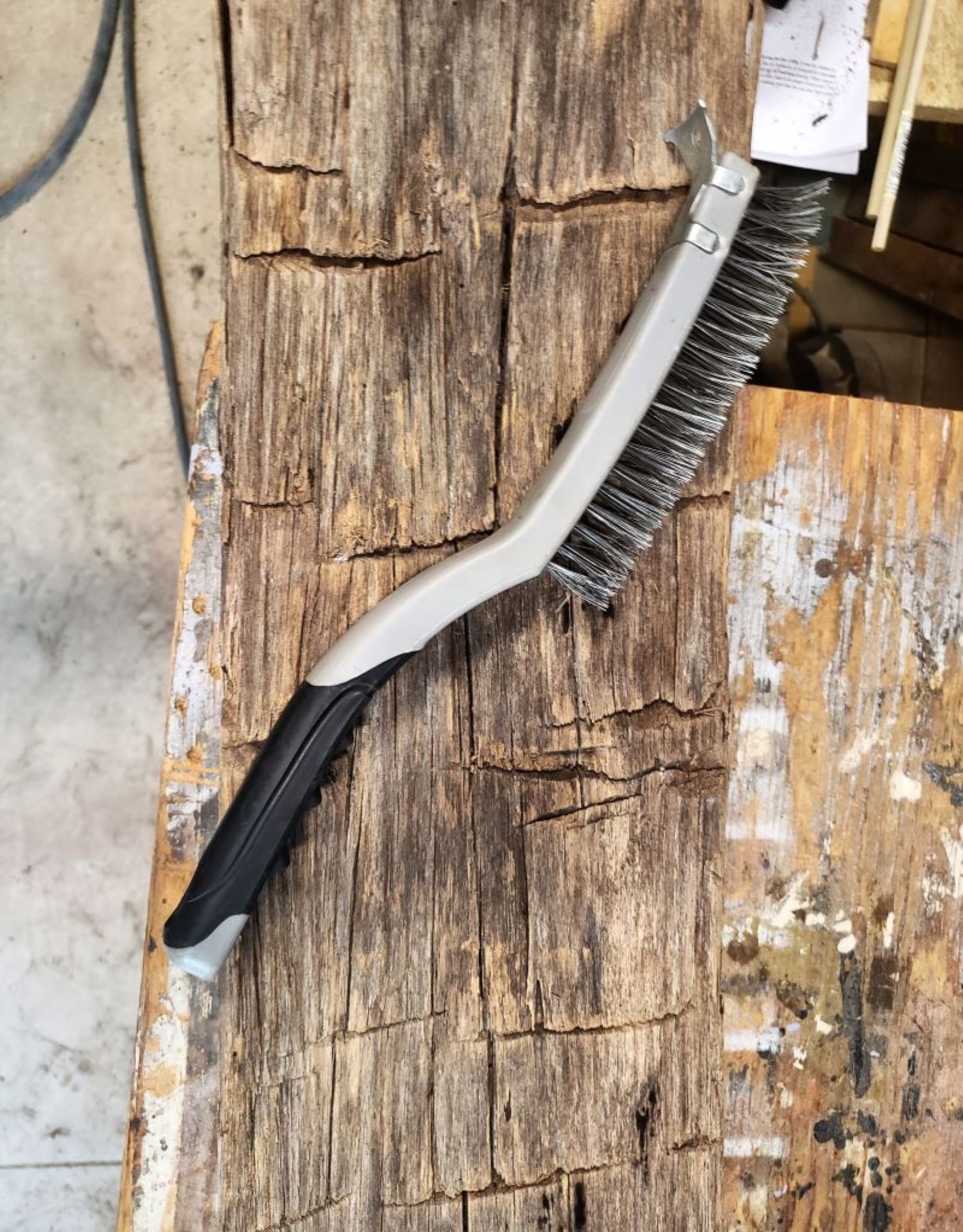 Wire brush, used for cleaning beams, sitting on top of a hand hewn barn beam